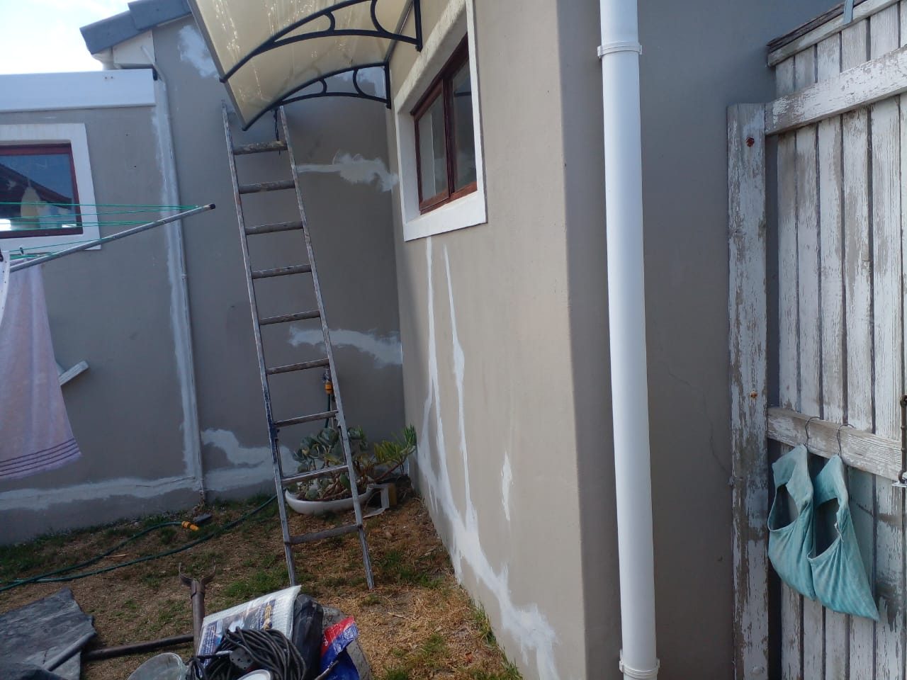 New gutter and downpipe installed on a plastered house wall