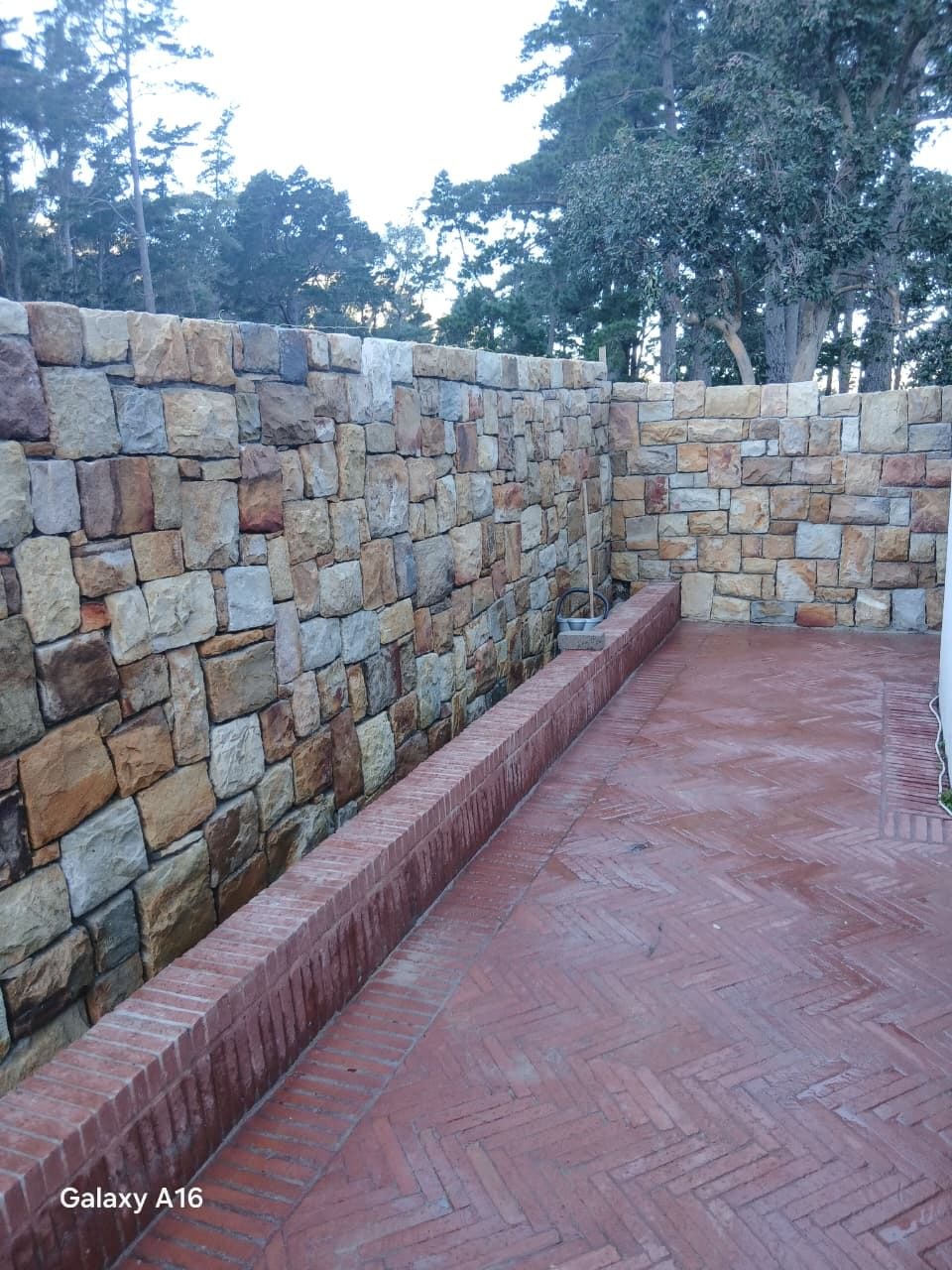 Herringbone brick paving framed by natural stone walls in a Cape Town garden
