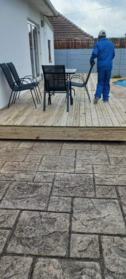 Timber deck being cleaned and restored next to patterned paving